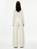 back view of a woman wearing a white outfit with wide-leg pants on a white background. #color_white