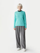 Person wearing a turquoise sweater and gray pants on a white background. #color_aqua-green #ai-image