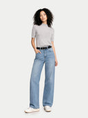 Woman wearing a gray shirt and light blue jeans on a white background. #color_urban-gray #ai-image
