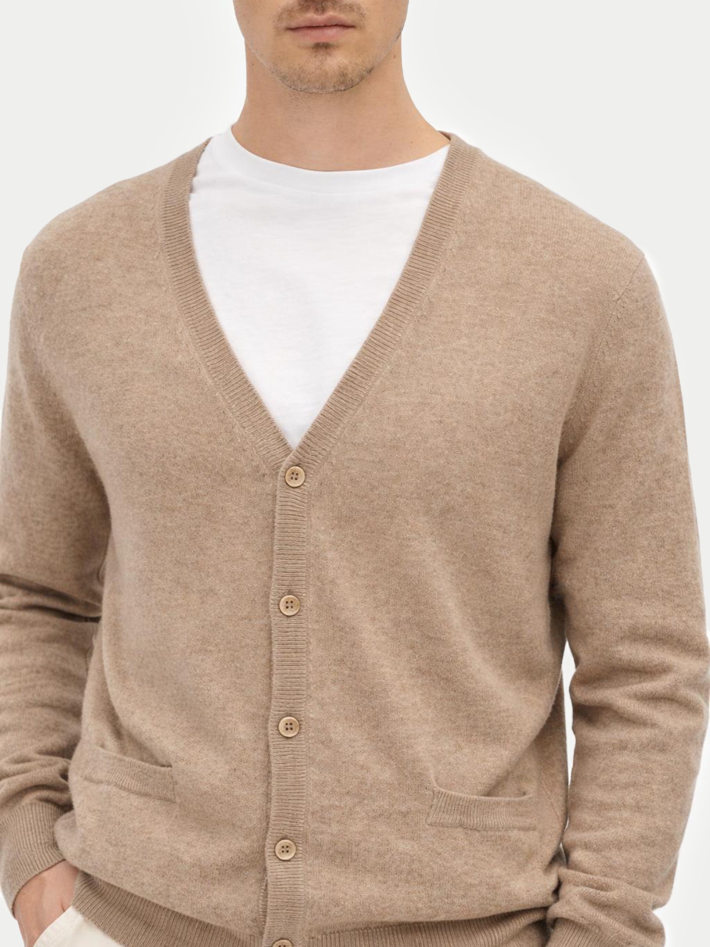 Man wearing a beige cardigan over a white shirt on a light gray background