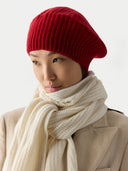 Person wearing a red knit hat and beige scarf on a white background #color_warm-red