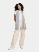 Woman wearing a light gray scarf, white shirt, beige pants, and white sneakers on a white background. #color_urban-silver #ai-image