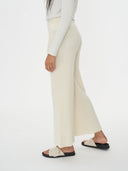 Person wearing white ribbed pants and sandals on a white background. #color_white