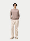 Man wearing a mauve sweater and beige pants on a white background.