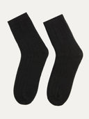 A pair of black unisex cashmere trim knit bed socks. #color_black