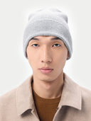 Person wearing a gray knit beanie and beige coat on a white background. #color_urban-silver