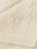 Close-up of a cream-colored knitted sweater with a brand tag. #color_off-white