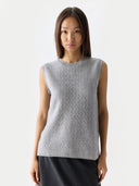 Woman wearing a light gray sleeveless knitted top against a white background #color_high-rise