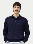 Man wearing a navy blue sweater against a light gray background.