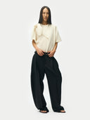 Person wearing a white top and black pants on a white background. #color_black