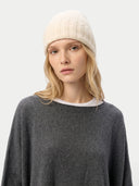 Person wearing a white knit beanie and gray sweater on a light gray background. #color_off-white #ai-image
