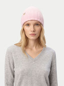 Woman wearing a pink knit beanie with a logo on a white background. #color_pink #ai-image