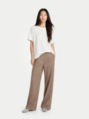 Woman wearing a white top and brown pants on a white background. #color_taupe #ai-image