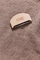 Wooden comb with GOBI logo removing pilling from a knit, close-up overhead view
