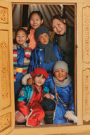 Family in deel robes, hats and scarves at a ger door celebrating Mongolian Lunar New Year