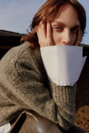 Cashmere fashion trends close-up: model in textured knit jumper layered over a white shirt cuff