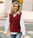 Smiling model in a V-neck cashmere knitted vest over a shirt and jeans, walking outdoors, front view