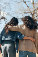 Two women seen from behind in chunky knit jumpers, blue and beige, layered for transitional weather with cashmere