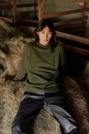 Model in green cashmere crewneck jumper and dark trousers, a capsule wardrobe essentials look, front view