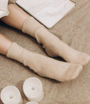 Ribbed beige knitted socks worn at home, showing the benefits of wearing socks beside candles and a notebook