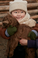 Child in cream knitted hat and scarf holding a brown cashmere goat kid, illustrating cashmere supply chain transparency