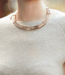 Close-up of ribbed light grey cashmere natural fibre jumper worn with a metal collar necklace