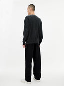 back view of a man wearing a dark gray sweater and black pants on a white background. #color_charcoal