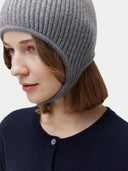 Person wearing a gray knit beanie on a plain background