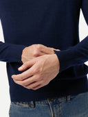 Person wearing a navy sweater with hands clasped in front. #color_dark-indigo