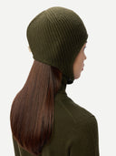 Person wearing a green knit beanie and coat on a white background