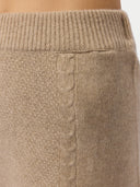 Close-up of a beige knitted sweater with cable pattern.