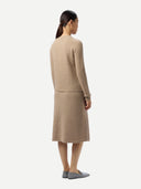 back view of a woman wearing a beige suit on a white background.