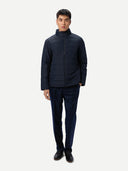 Man wearing a dark blue quilted jacket and pants on a white background