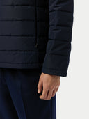 Navy blue puffer jacket worn by a person on a light gray background