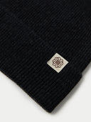 Black knit beanie with a logo tag on a white background