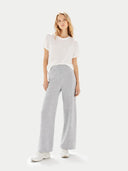 Woman wearing a white t-shirt and gray pants on a white background. #color_light-gray #ai-image