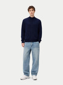 Man wearing a navy sweater and light blue jeans on a white background. #color_navy-blue #ai-image