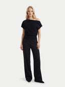 Woman wearing a black off-shoulder top and wide-leg pants on a white background #color_black