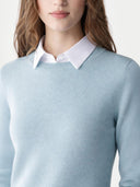 Light blue sweater worn by a person with a white shirt underneath on a plain background #color_cloud-blue