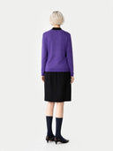 back view of a woman wearing a purple sweater and black skirt on a white background. #color_dusty-grape #ai-image