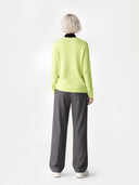 Person wearing a light green jumper and grey pants on a white background #color_white