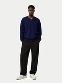 Man wearing a navy sweater and black pants on a white background
