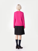 Person wearing a bright pink jumper and black skirt on a white background #color_black