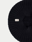 Black knit beanie with a visible brand label on a light gray background