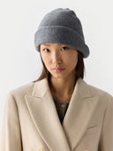 Person wearing a gray knit beanie and beige coat on a white background #color_gray