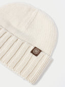 Beige knit beanie with a brand logo on a light gray background. #color_off-white