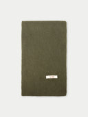 Green knitted scarf with a brand label on a light gray background