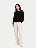 Person wearing a black sweater and white pants on a white background #color_black