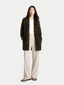 Woman wearing a dark green cardigan over a white top and beige pants on a white background  #color_olive-green