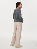 back view of a woman wearing a gray sweater and beige pants on a white background. #color_dark-gray